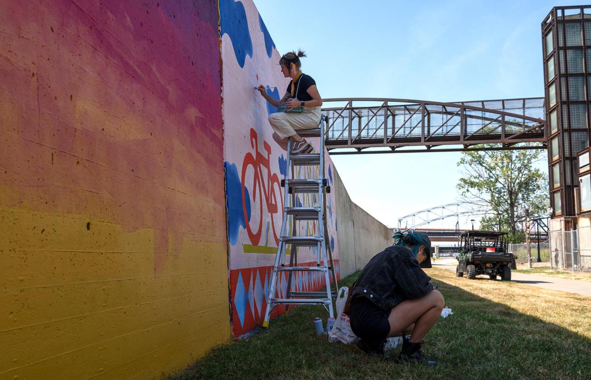 Felicia Koloc paints a star on her piece “Joy Ride” while Emily Ding redesigns her mural on Friday, Sept. 15, 2023, at the Riverfront Heritage Trail in Kansas City. “This seems pretty accessible to everybody and it’s a free space,” Koloc said. “ You don’t have to be of a certain background to appreciate this, it’s nice to be a part of a project like that.”