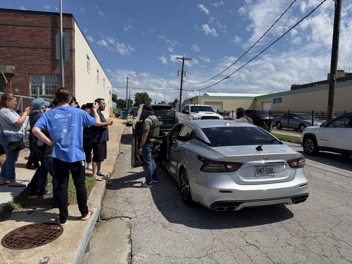 Bystanders and community advocates gather around a federal agent after a person in handcuffs was put into a car at La Fontanella Foods in Kansas City on Thursday, July 9.