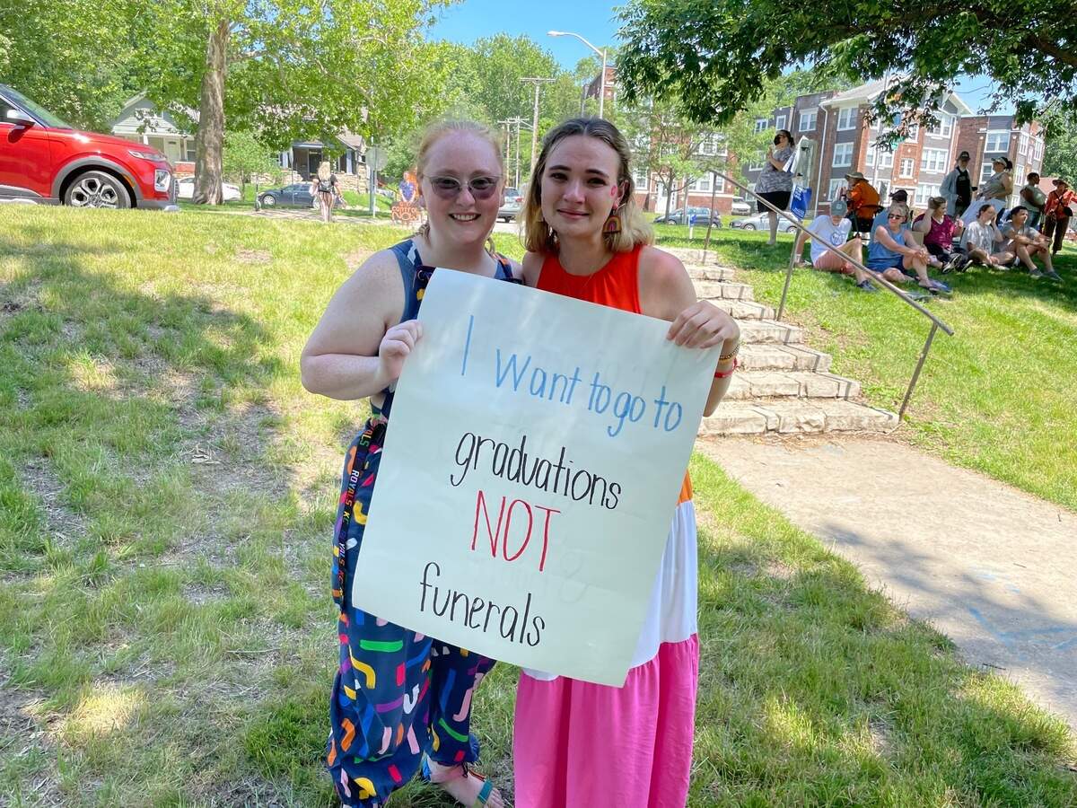 Danielle Christian, 22, and Tara Rogers, 21, hold a sign with “I want to go to graduations not funerals” written in different colored markers at Gillham Park, Saturday. Christian teaches special education students and Rogers teaches preschool. Both their students would be unable to defend themselves in a mass shooting, despite attempts to prepare through active shooter drills. They said easy access to guns has caused them to worry for their lives and the lives of their students.