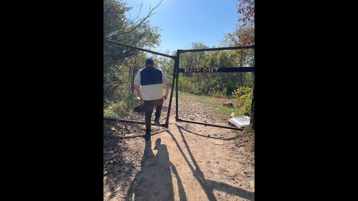 Nick Allen, an outreach worker with the City of Kansas City, steps through a gate at the entrance of an encampment near the Truman Sports Complex.