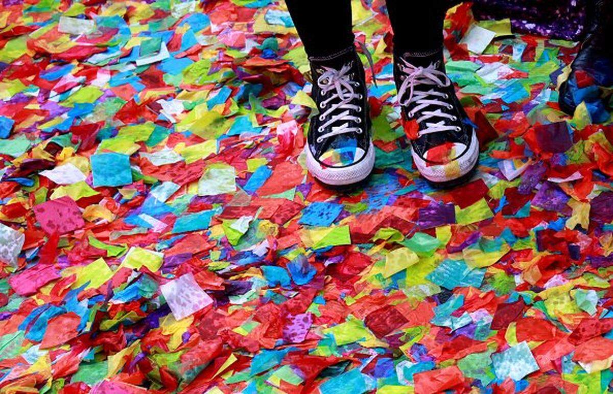 People stand in rain soaked confetti in Times Square on Monday during New Year's Eve rehearsals as part of the Planet Fitness test air worthiness of confetti in New York.