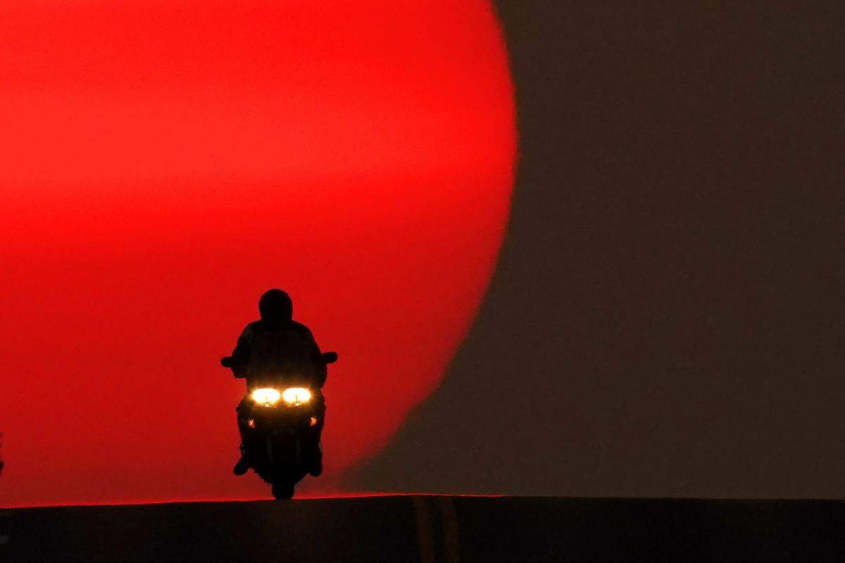 A motorcyclist is silhouetted against the setting sun Sunday in Shawnee. Sunsets have been more vibrant than normal recently as smoke from western wildfires drifts across the United States.