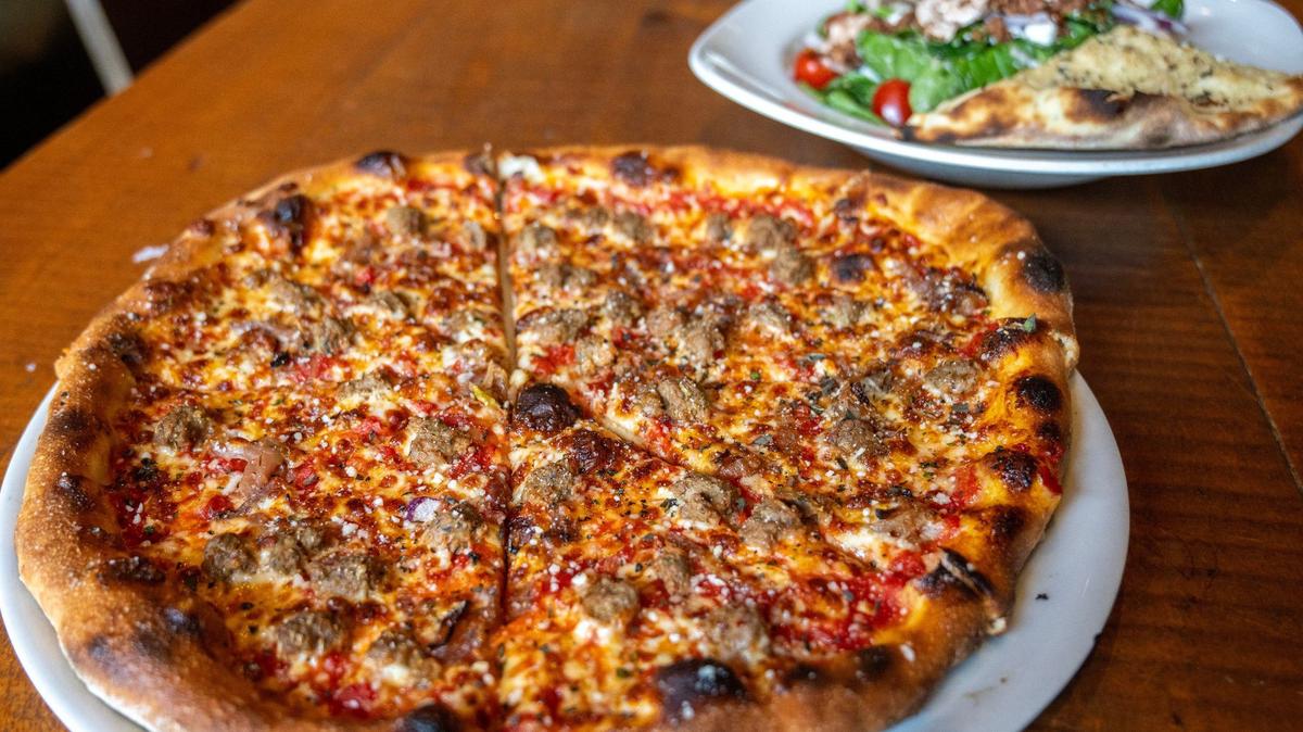 A sausage and caramelized onion pizza paired with the spinach and goat cheese salad is seen at Spin Pizza on May 14 in Kansas City.