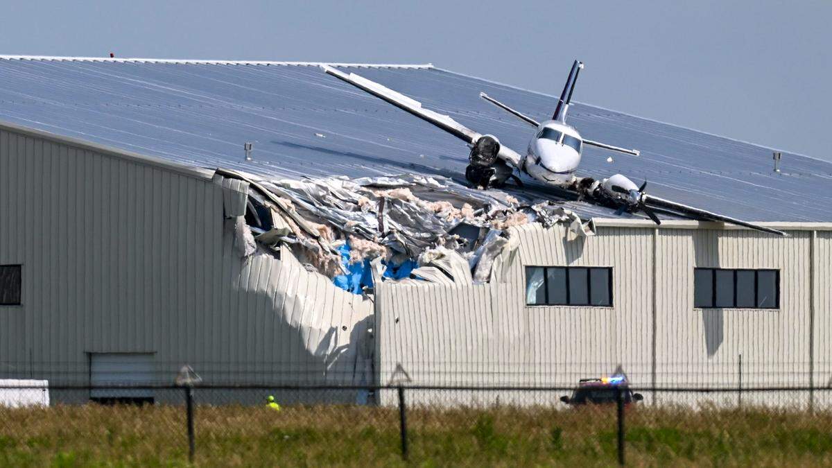 A Beechcraft airplane rests on the roof of a building at New Century AirCenter after it made a crash landing that left it on the roof on Monday, June 16, 2025.