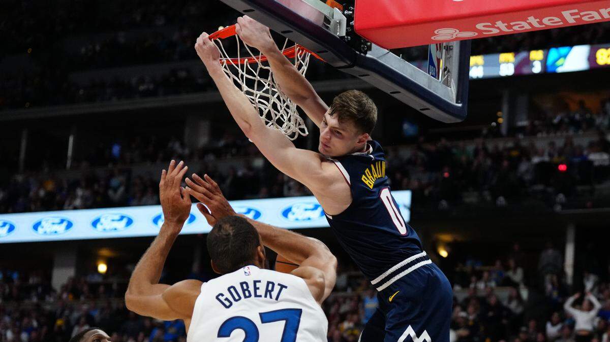 Denver Nuggets guard Christian Braun (0) finishes a dunk over Minnesota Timberwolves center Rudy Gobert (27) in the second half at Ball Arena on April 10, 2024.