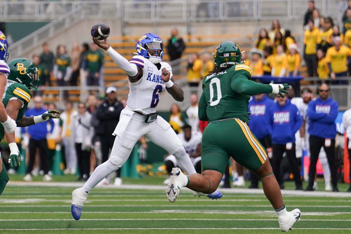 Kansas Jayhawks quarterback Jalon Daniels (6) throws a pass under pressure from Baylor Bears defensive lineman Jackie Marshall (0) during the first half at McLane Stadium on Nov. 30, 2024.