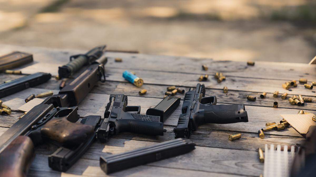 Rifle and guns stored on wooden table with bullets ammunition clips and shells. Military equipment. Firing range. Horizontal shot. High quality photo