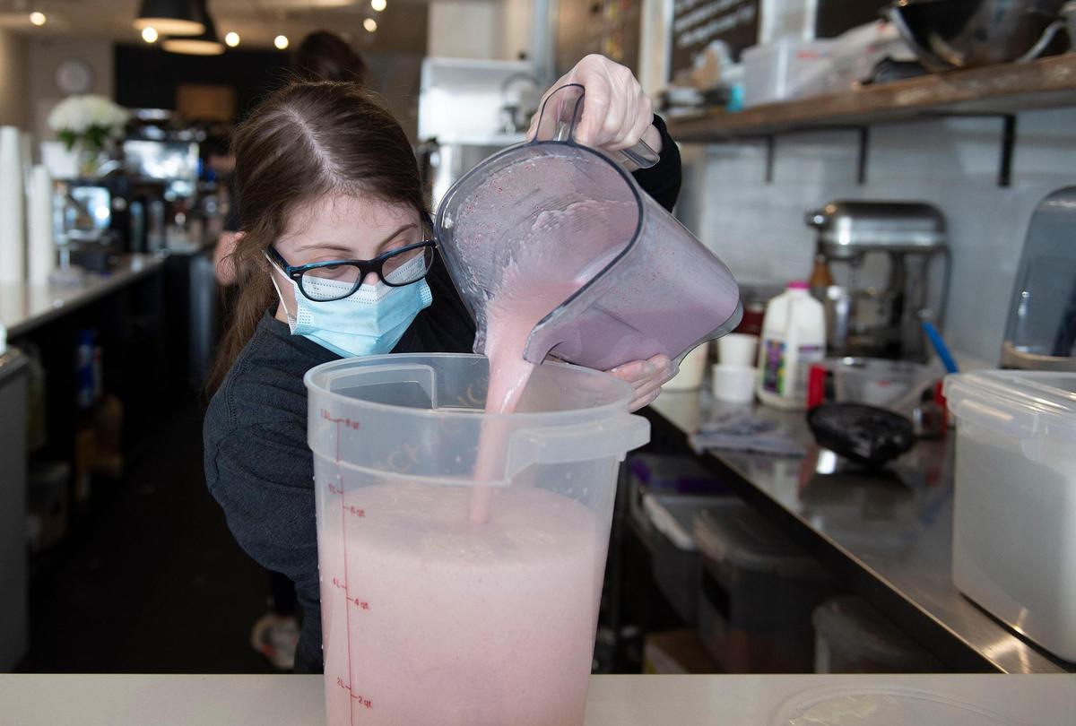 Lucy Wagner, 23, pours a batch of strawberry ice cream into a container while working Wednesday at The Golden Scoop. Wagner works three days a week and said, “I love it.”