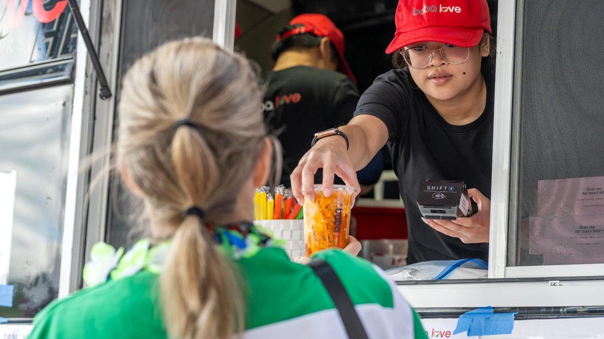 An employee from the Boba Love food truck hands an order to a customer during the 4th Annual Taste of AAPI festival on Saturday, May 3, 2025, in the West Bottoms district of Kansas City. The event celebrates Asian American and Pacific Islander Heritage Month with food vendors, cultural performances and community activities.