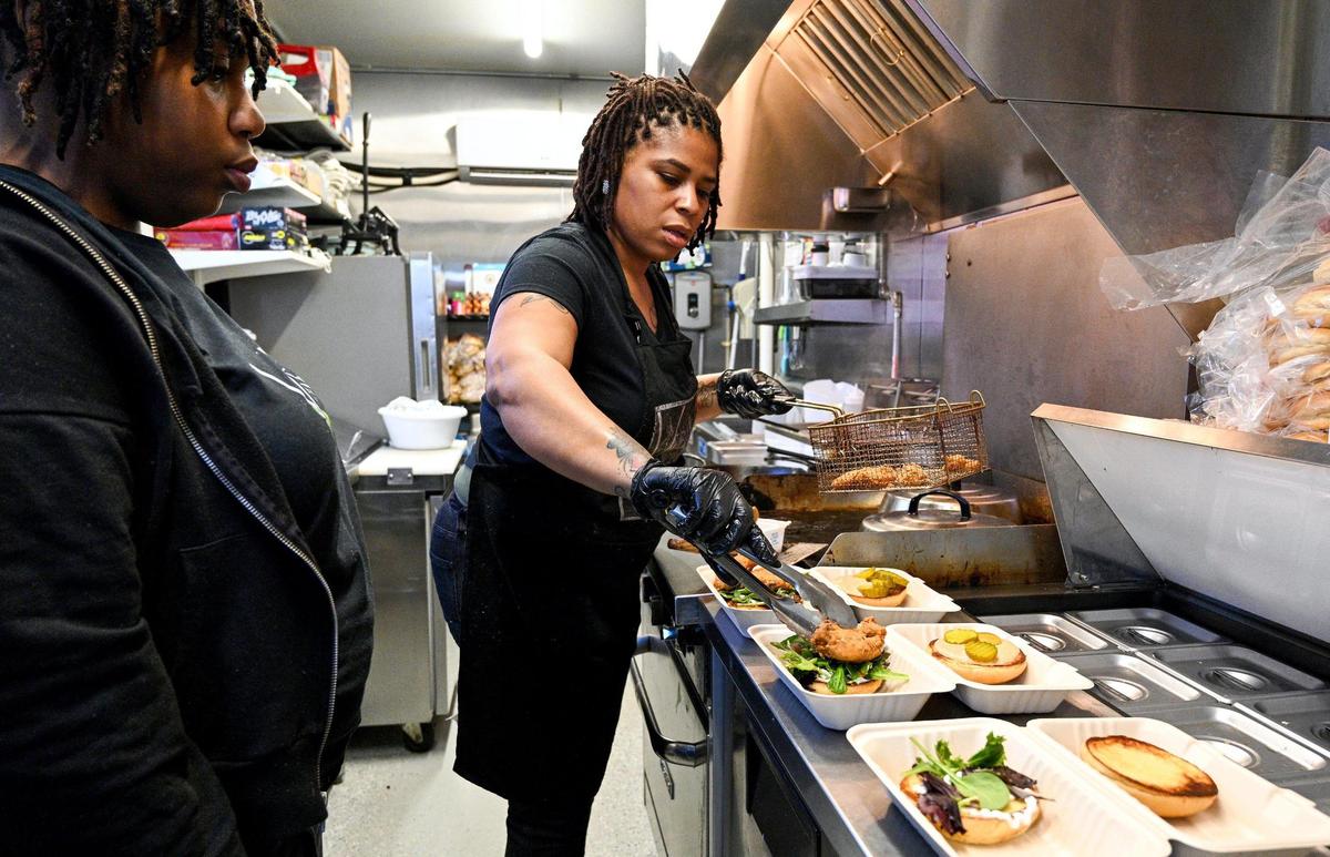Teeshia Madge prepares an order at her Vegan Crave Burgers and Bakery in the Iron District in North Kansas City as her daughter and assistant, Ravionne Samuels, left, watches. She’s on a mission to promote healthier fast food and dispel the belief that vegan food can’t be delicious.