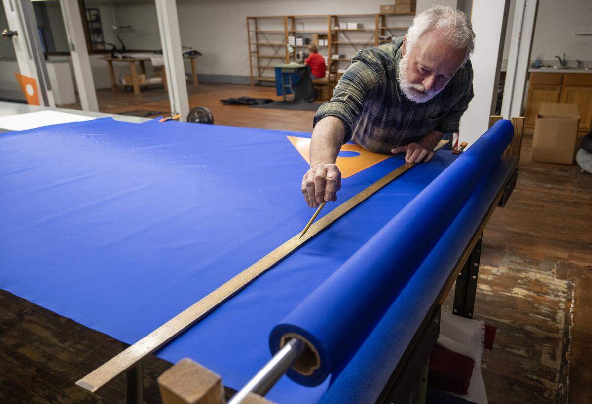 Randy Carney cuts the bright blue background fabric to make a flag of Curaçao on Thursday, Jan. 8, 2025, at All Nations Flag Co., in Kansas City. Curacao is the smallest country participating in the FIFA World Cup matches in Kansas City this summer.