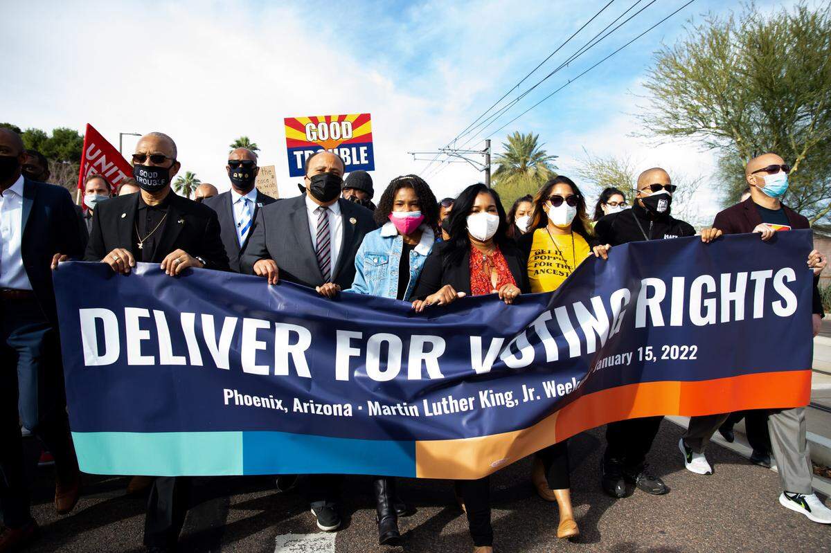 From left, Dr. Warran H Stewart Sr., Martin Luther King III, Yolanda Renee King, Ardrea Waters King and Chanel Poe carry a sign for the Deliver For Voting Rights organization in Phoenix on Saturday. As the nation prepares to mark the birthday of the Rev. Martin Luther King Jr., some members of his family are spending it in conservative-leaning Arizona to mobilize support for languishing federal voting rights legislation.