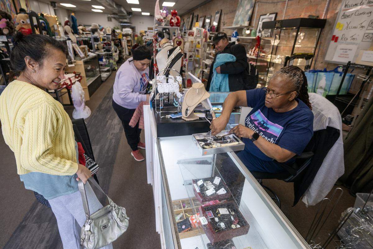 Jo Babaran, left, a founder/manager of Troost39, a thrift store, brings purses and watches to the front counter where Renee Tolbert will ready the merchandise in the case on Thursday, Jan. 22 2026, in Kansas City.