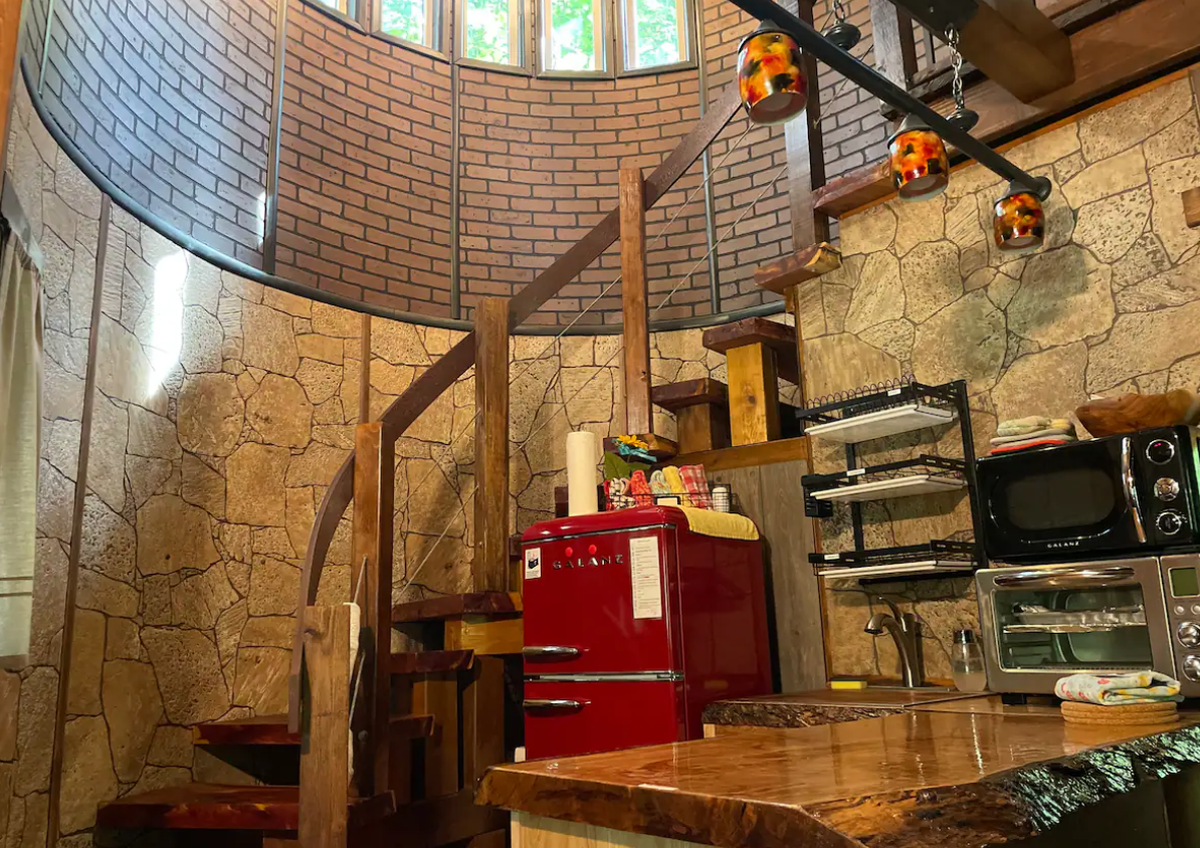 The Whispering Elm Treehouse sleeps four and features a winding staircase near its kitchen.