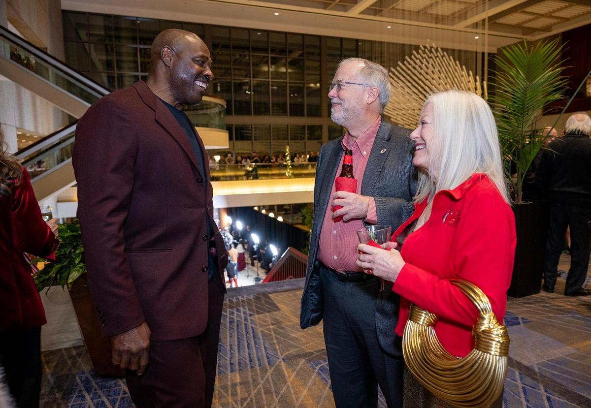 Christian Okoye, left, talks with Don Hall and Cindy Heckman at the premiere screening of Hallmark’s “Holiday Touchdown: A Chiefs Love Story,” on Saturday.