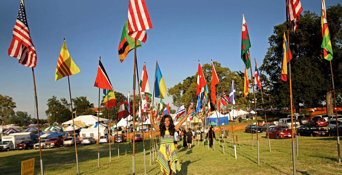 A woman stands in front of international flags in a park. 