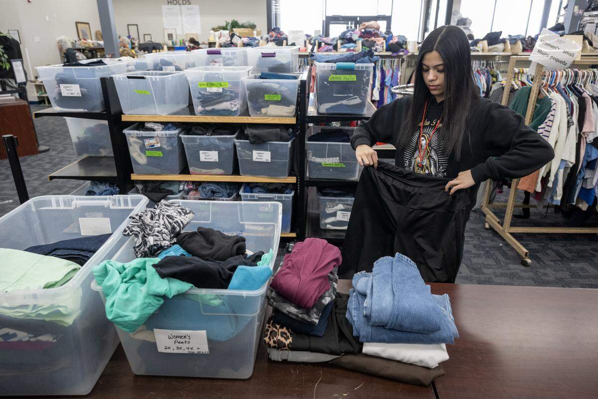 Volunteer Emilee Vasquez (left) restocks women's clothing at Starfish Project on Thursday, Feb. 12, 2026, in Olathe. The organization is a nonprofit that provides essential items free of charge to those in need. They have recently received notice that it must relocate the operation.