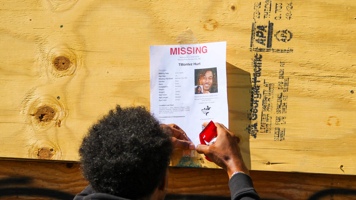 Steven Wright hangs a missing person flyer with information about T’Montez Hurt on an abandoned building near Troost and 85th streets in Kansas City.