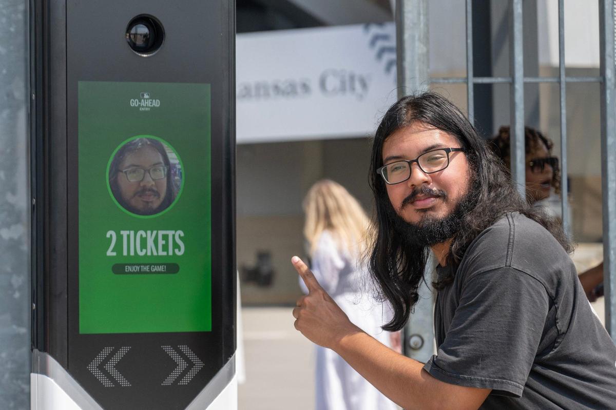 Joseph Hernandez, Kansas City Star service reporter, points to a photo of himself to showcase how the Go-Ahead Entry technology is utilize during a press conference outside of Kauffman Stadium.