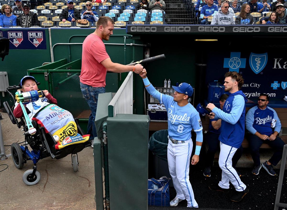 Kayden Rhoades was given 24 hours to live at birth, but 15 years later he threw out the first pitch on Thursday at Kauffman Stadium with the loving help of his family. Rhoades, who was born with hydranencephaly, used a device his father Dustin, above, created for him to complete the feat. Kayden also received a bat from Royals’ second baseman, Nicky Lopez, right. It was a bucket list day in every way for the family from Sioux City, Iowa.