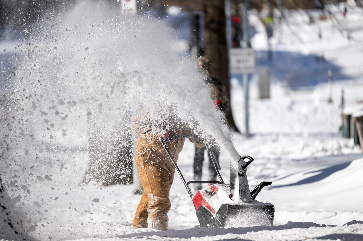 An associate from Terra Management clears snow from the sidewalk along Armour Boulevard on Monday, Jan. 6, 2025, in Kansas City.