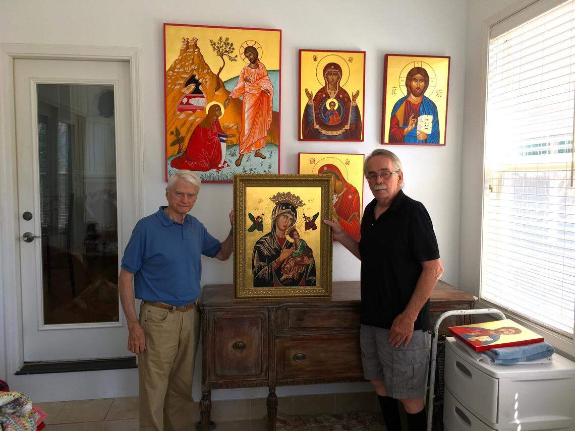 John Gregory, left, presents some of the artwork of artist Tom Dolphens.