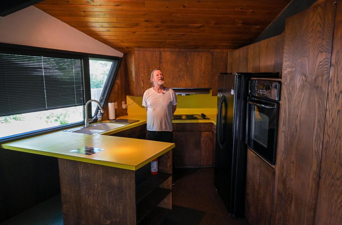 Lantz Stephenson stands in the mostly-original kitchen of the home which features bright yellow counter tops.