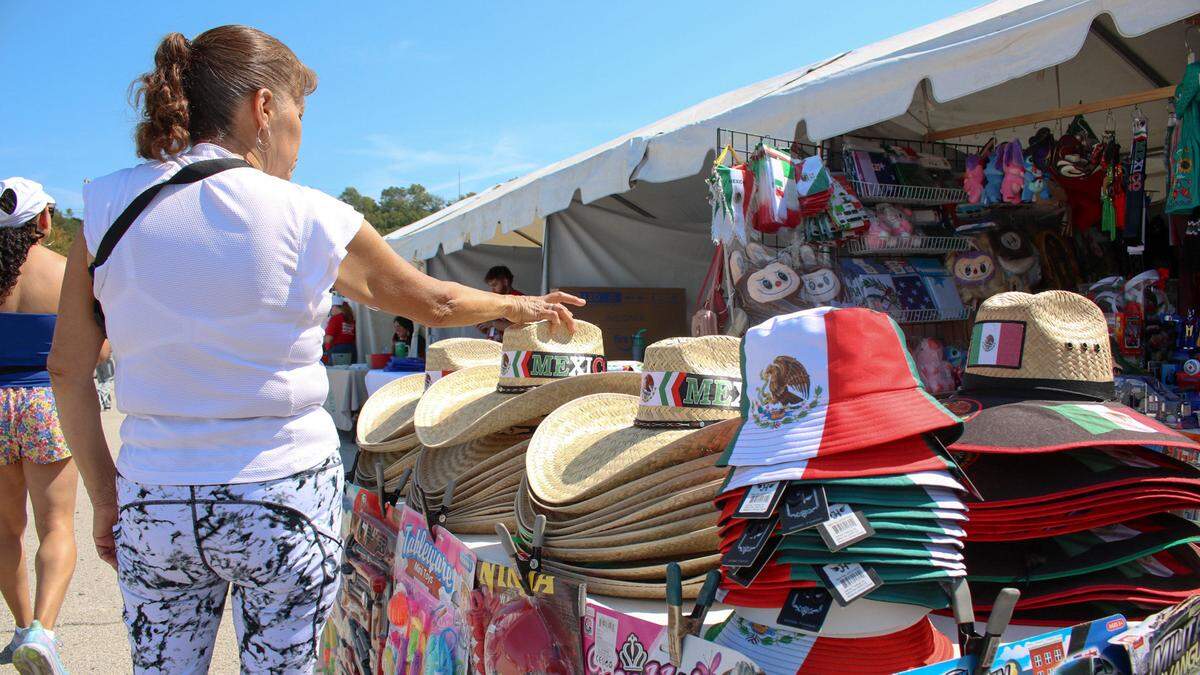 People look at straw hats sitting on a table at a vendor booth at Fiesta Hispana. There were dozens of vendors selling souvenirs at the three-day event celebrating Hispanic heritage.