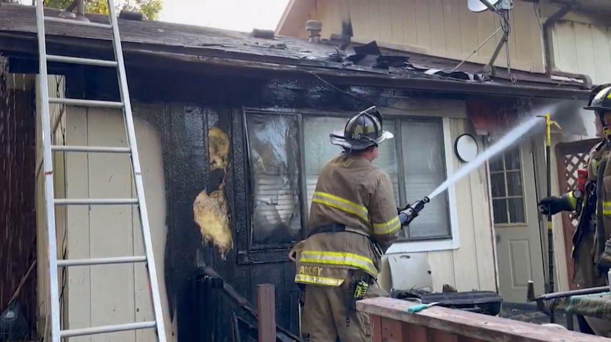 An Overland Park firefighter sprays water on a Merriam duplex that burned July 6. No one was injured.