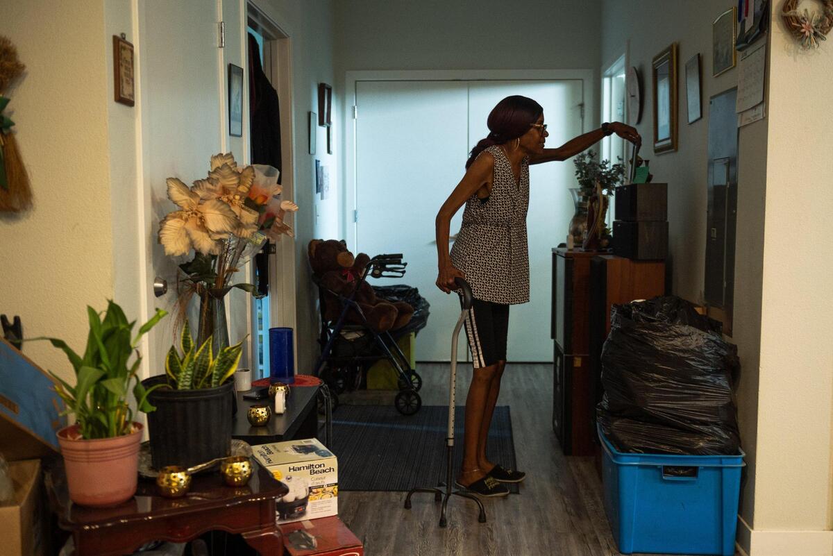 Vivian Jackson adjusts an image of her daughter at her apartment on June 15 in Kansas City. Due to a stroke and the falls she has had in her apartment, Jackson suffers from constant pain and limited mobility.