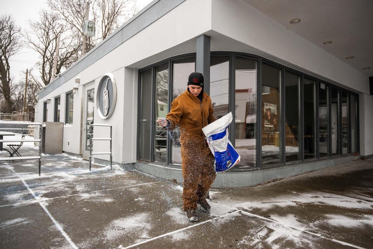 A young man named Nixom spreads ice melt in front of a Chipotle on 39th Street in Kansas City on Wednesday, Feb. 12, 2025. Kansas City was blanketed with snow overnight and into the early morning Wednesday.