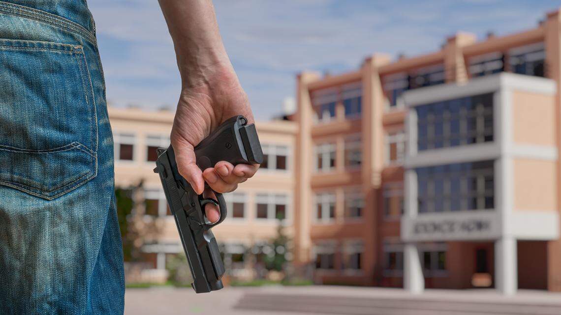 Gun control concept. Young armed man holds pistol in hand in public place near high school. school shooting violence weapon shoot mass