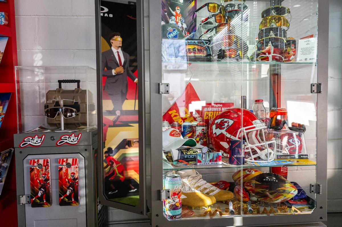 A collection of Chiefs-themed products, designed and made by Sike Style Industries, is showcased behind a glass display case at their art studio in Kansas City.