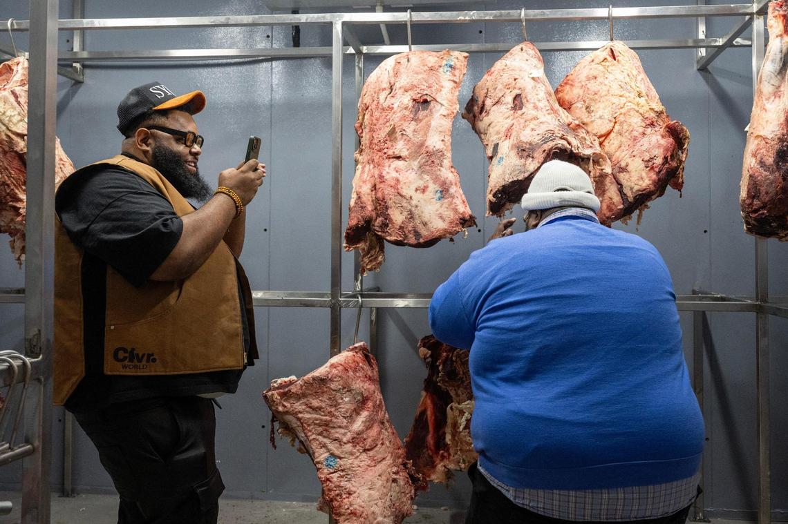 Glenn Robinson, left, and Jerimiah Lyles record a video in the meat storage area for a food review at The Upper Cut KC in Liberty.
