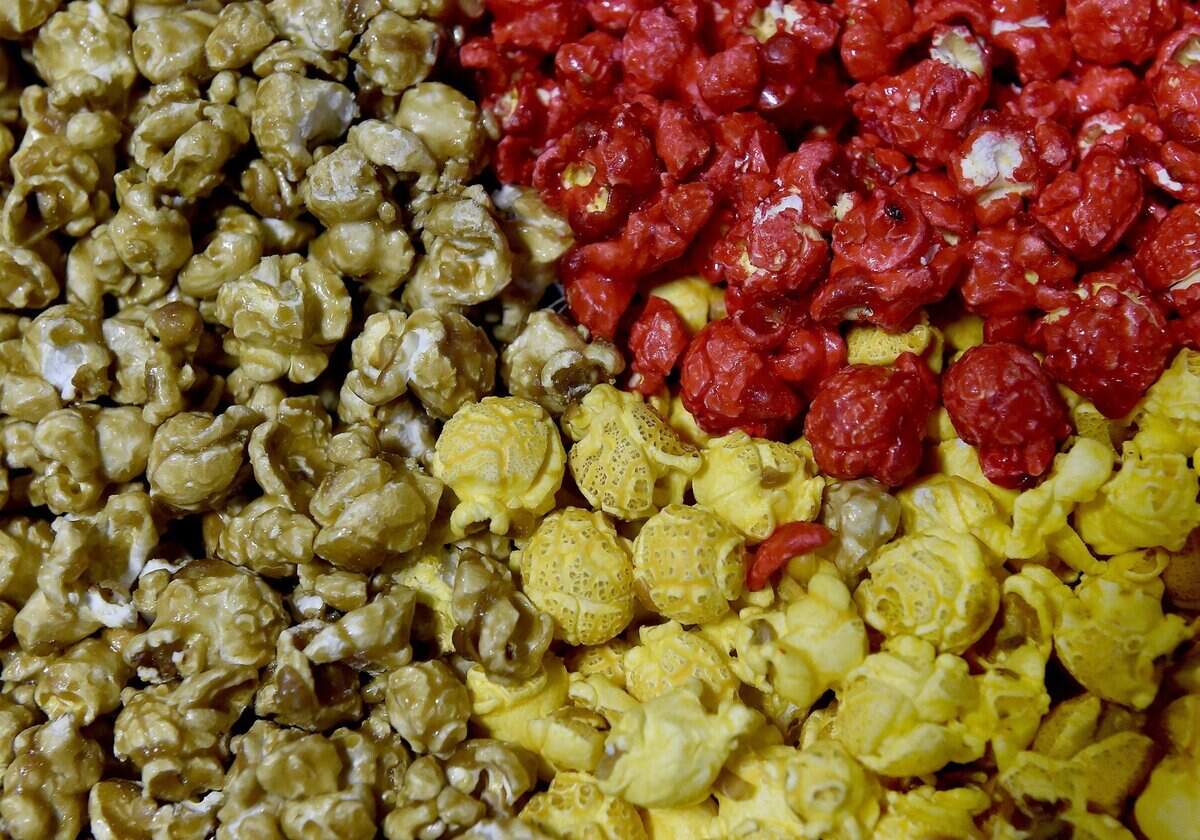 Topsy’s popcorn factory in the Waldo neighborhood is busy filling holiday cans. Caramel (from left, clockwise) cinnamon and cheese popcorn.