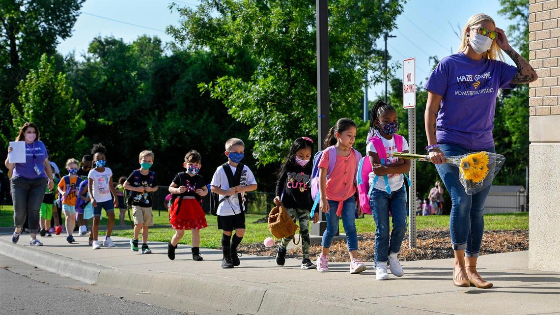Holding the flowers presented to her by a student on the first day of school, kindergarten teacher Adrianna Pence leads her class toward the entrance to Hazel Grove Elementary in Kansas City, Kansas, earlier this month.