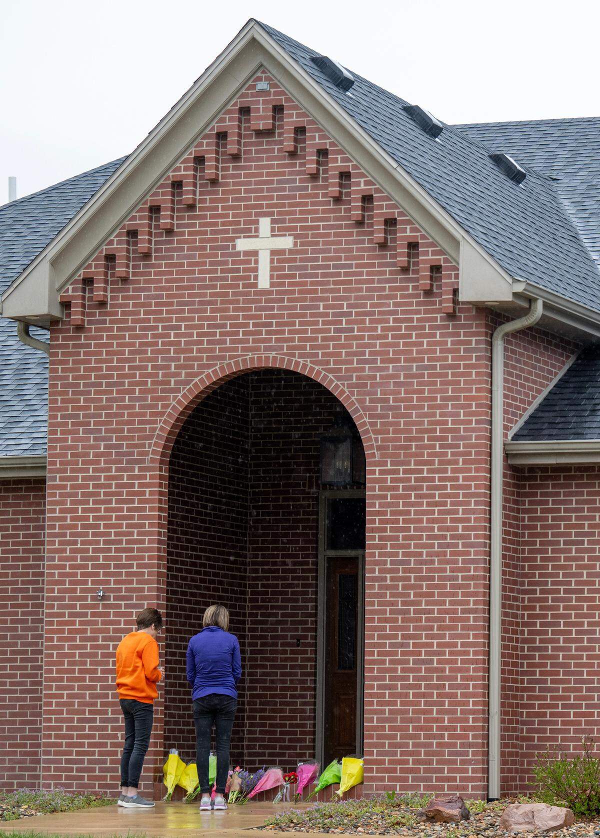 Two women leave flowers and pay tribute to Fr. Arul Carasala, a Catholic priest, was shot and killed Thursday, by a man near the parish rectory of Saints Peter and Paul Catholic Church in Seneca, Kansas.
