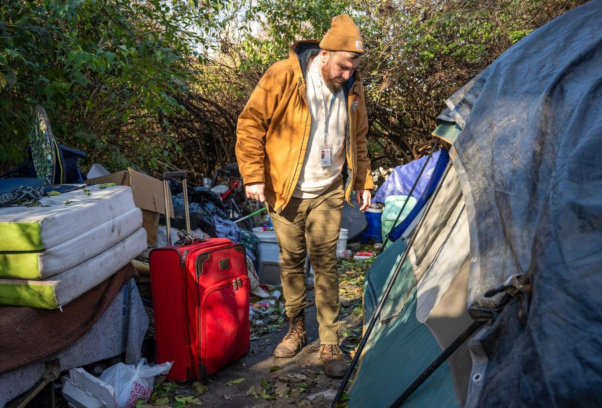 Nick Allen, the street outreach coordinator for the Office of Unhoused Solutions, talks to a woman inside a tent at homeless camp in Kansas City.