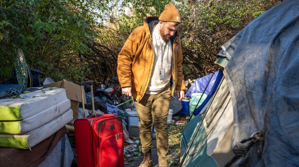 Nick Allen, the street outreach coordinator for the Office of Unhoused Solutions, talks to a woman inside a tent at homeless camp in Kansas City.