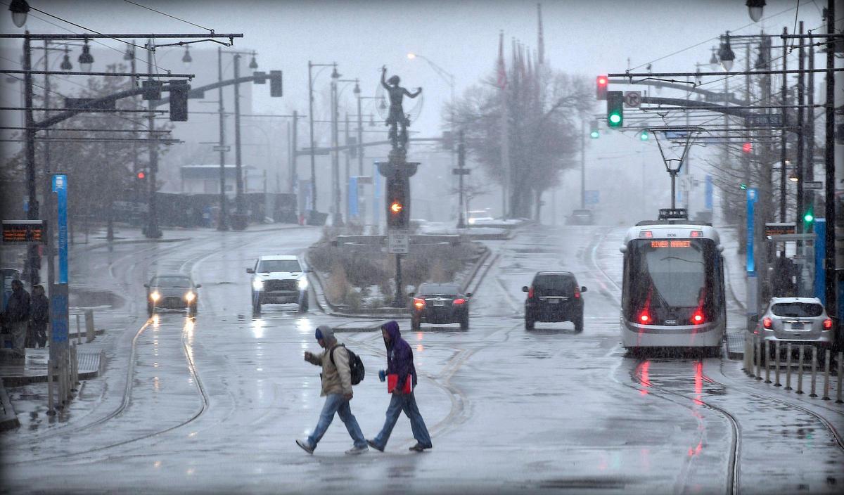 As snow fell throughout the Kansas City area Wednesday morning, a pair of pedestrians made their way across Main Street, near 9th Street, downtown. Kansas City should see between 1-3 inches of snow accumulation. Areas towards the east of Kansas City could receive up to 4 inches. An Arctic front will drop high temperatures into the teens on Thursday after they dip to around 6 degrees in the morning. On Friday, the predicted high will be about 30 after a low near 4.