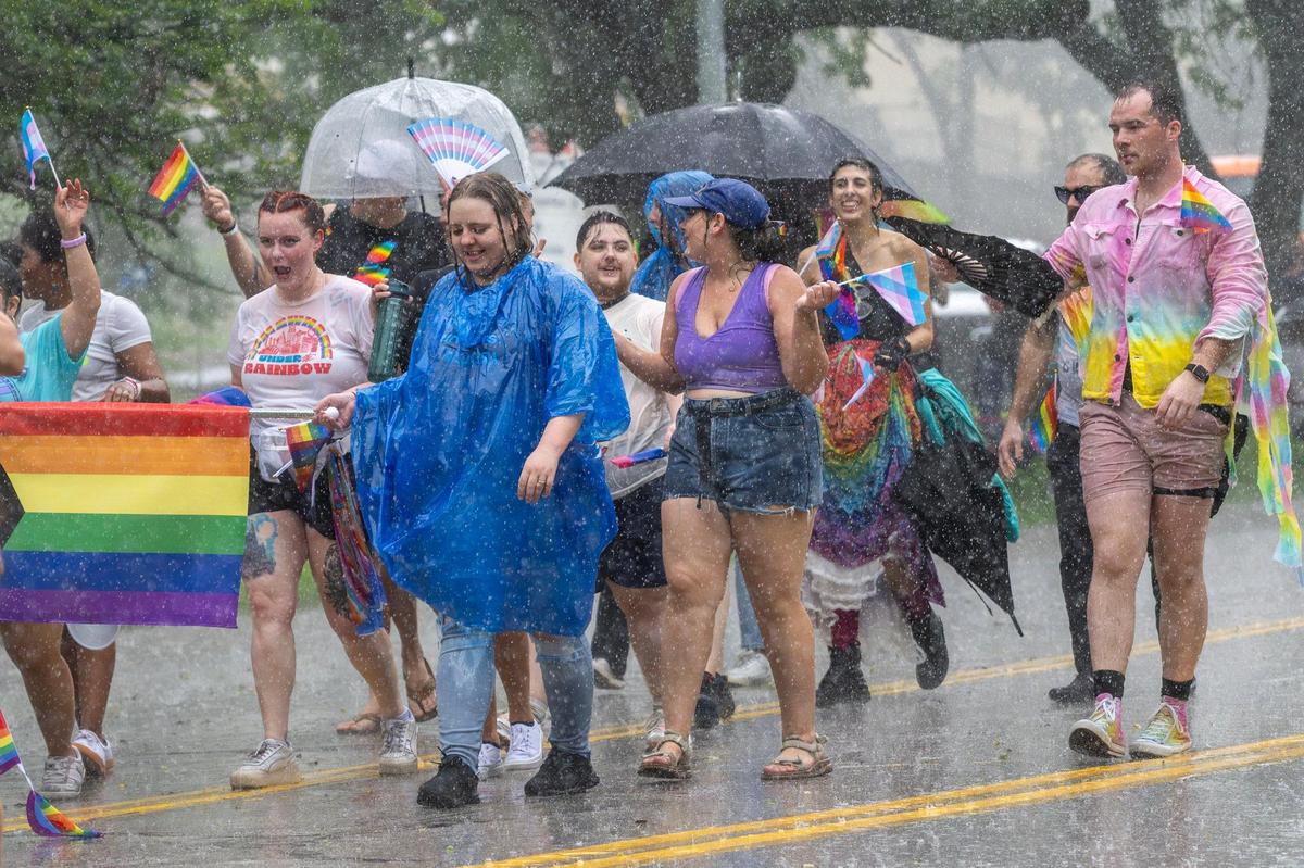 Heavy rain falls as parade participants walk along Mill Creek Parkway during the KC Pride Parade.