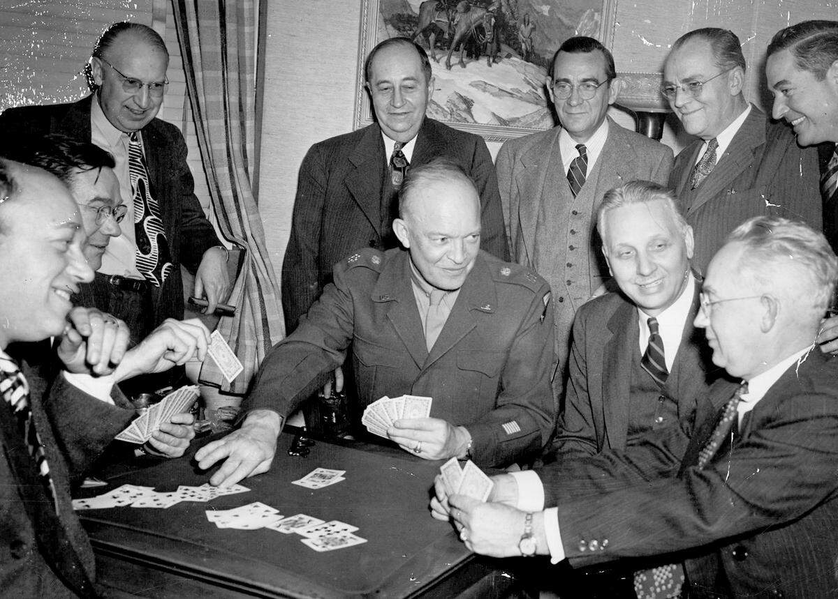 L. Russell Kelce, seated at left, partners with General Dwight D. Eisenhower during a bridge game at the Kansas City Club. Watching the action are fellow players and kibitzers, including Elmer F. Pierson and a gathering of local businessmen.