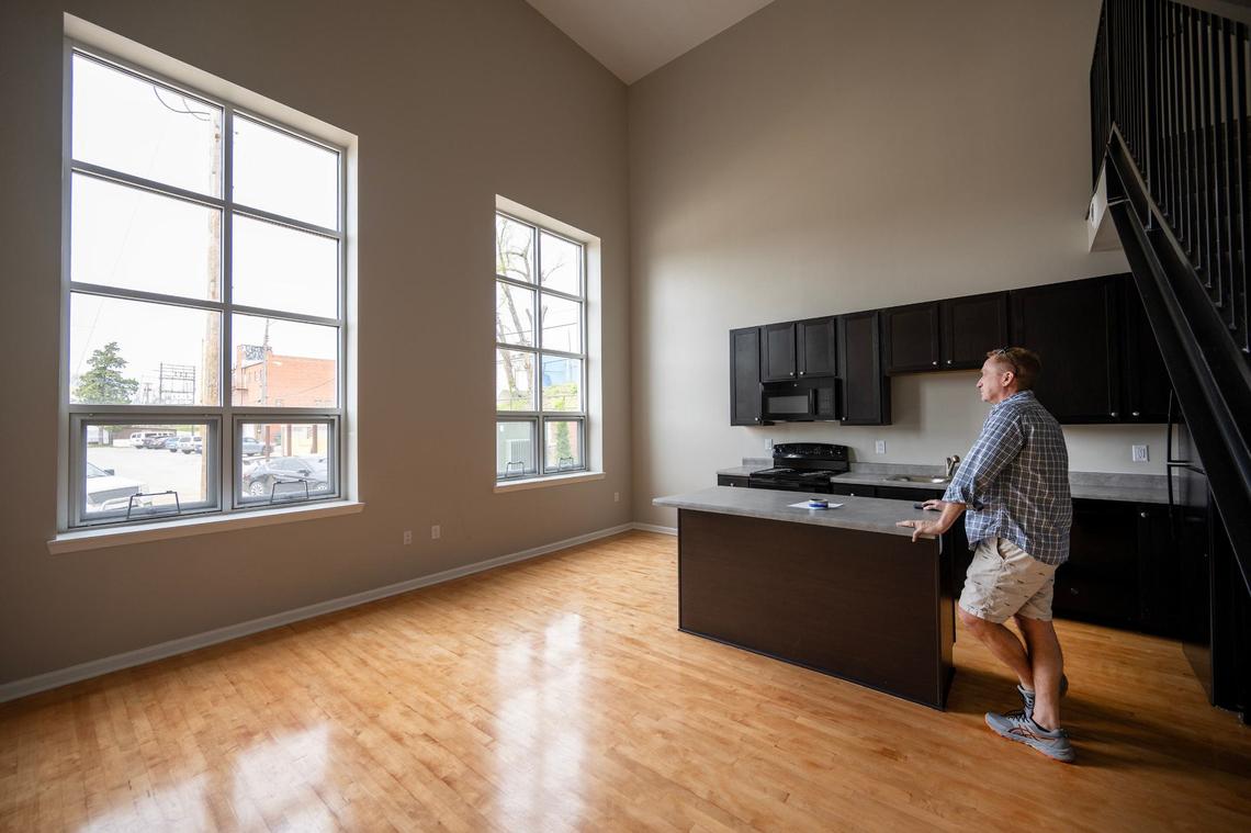 Developer Kelley Hrabe looks out the windows of an apartment in a converted racquetball court in Y Lofts. The two-story loft-style unit features a bedroom and bathroom on each floor. The floors, original to the racquetball court, were refinished for the apartment.