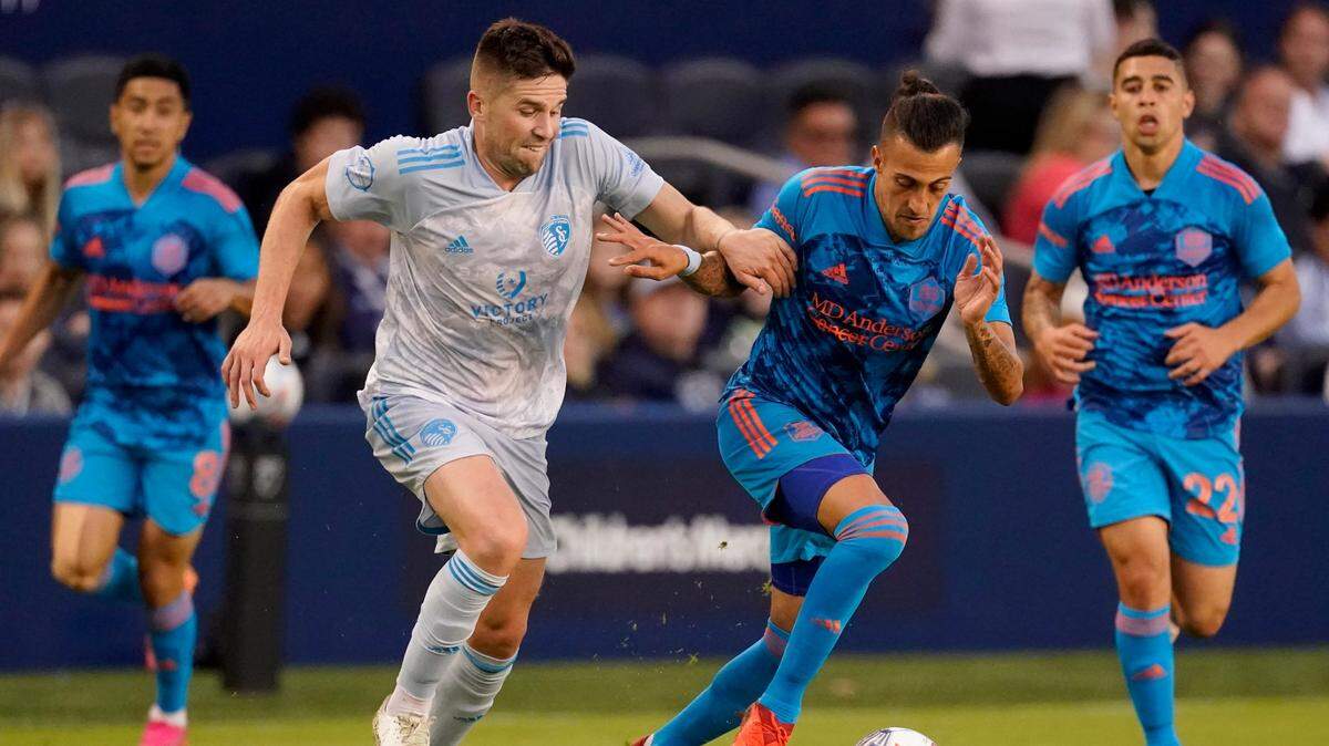 Sporting Kansas City defender Andreu Fontas, left, and Houston Dynamo forward Maximiliano Urruti chase the ball during the first half of an MLS soccer match Saturday, May 29, 2021, in Kansas City, Kan. (AP Photo/Charlie Riedel)