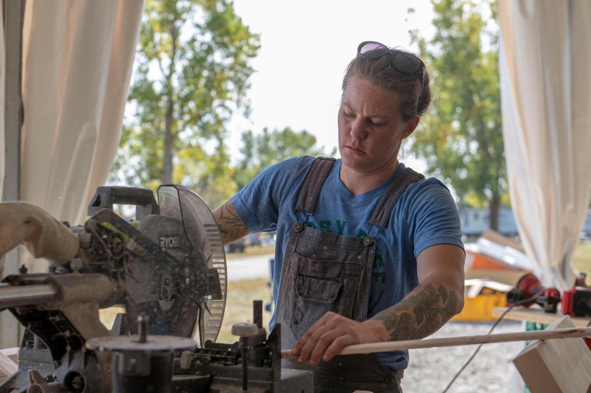 Marine Corps veteran and dedicated nomad Jessica Rambo cutting wood that will be installed as paneling inside the van she’s renovating for “Gutted.” 