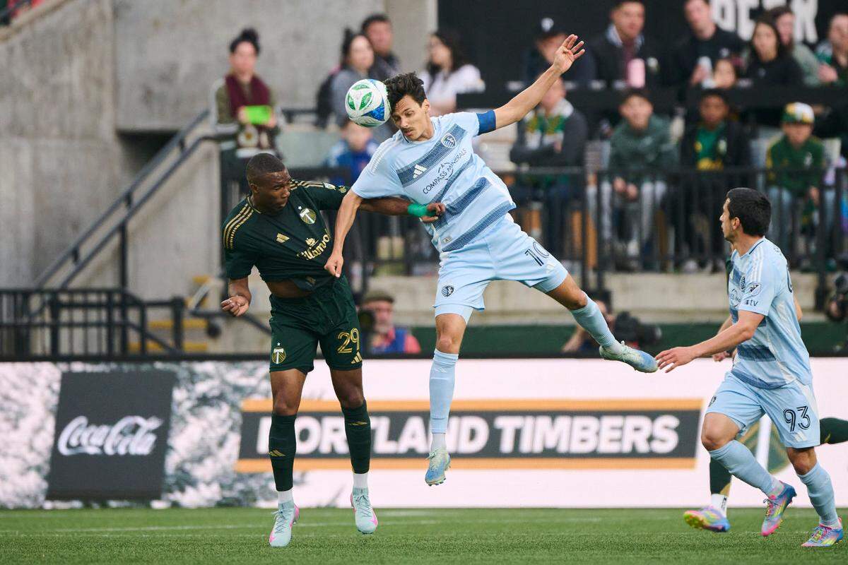 Sporting Kansas City forward Daniel Salloi, center-right, goes airborne against Portland Timbers defender Juan David Mosquera during a Saturday, May 10, 2025 Major League Soccer match at Providence Park in Portland, Oregon.