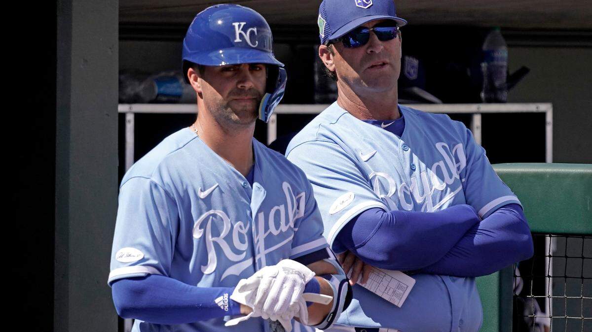 Kansas City Royals’ Whit Merrifield, left and manager Mike Matheny watch from the dugout during the second inning of a spring training baseball game against the Oakland Athletics Tuesday, March 22, 2022, in Surprise, Ariz. (AP Photo/Charlie Riedel)