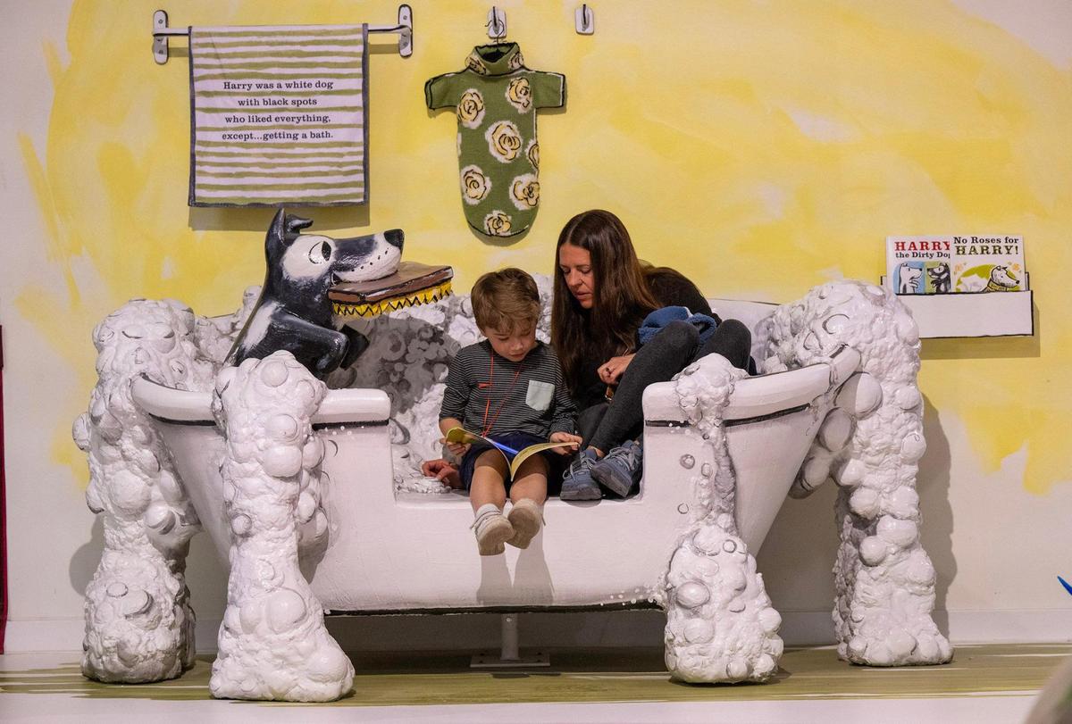 Henry Rentschler, 7, of Prairie Village reads “Harry the Dirty Dog” with his mother, Lauren Rentschler of Prairie Village, in the tub at the exhibit for the book.