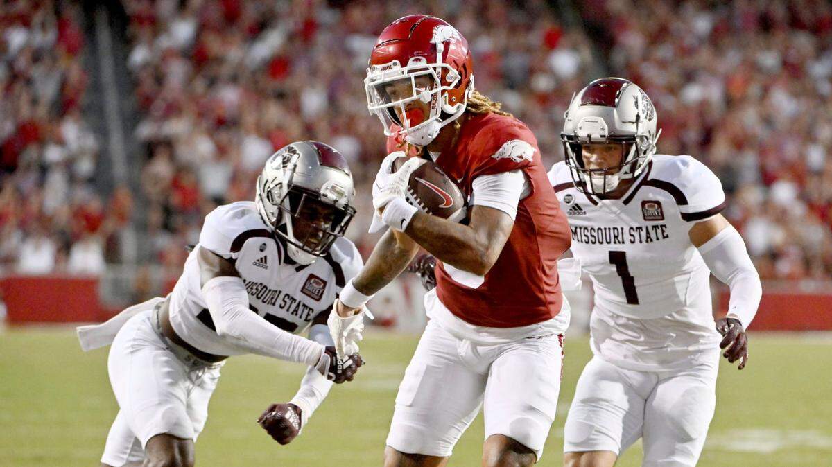 Arkansas wide receiver Jadon Haselwood, center, slips past Missouri State defenders Caleb Blake, left, and Aaron Harris to score a touchdown Saturday in Fayetteville, Ark.