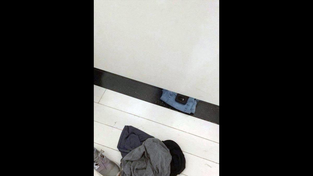 A cellphone photo taken by Emily in a dressing room at Forever 21 at Oak Park Mall shows a phone pushed under a changing room partition. Anthony DeLapp is charged with breach of privacy by photo or video in Johnson County District Court in the case.